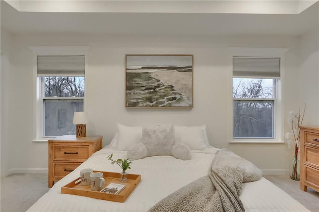 bedroom with light carpet, multiple windows, and baseboards