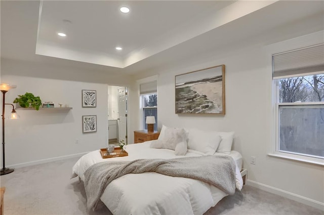 bedroom with light carpet, a tray ceiling, recessed lighting, and baseboards