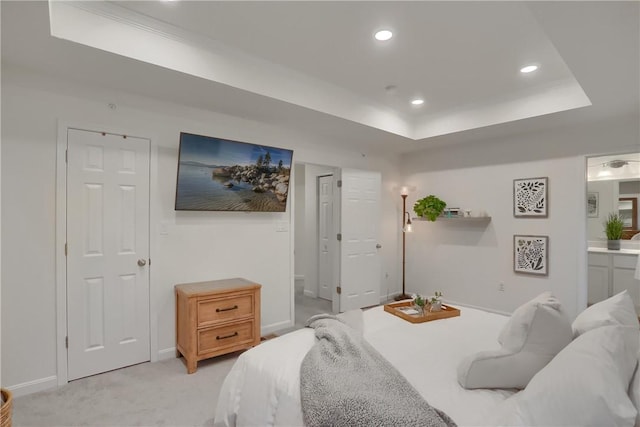 bedroom featuring recessed lighting, a raised ceiling, ensuite bathroom, light carpet, and baseboards