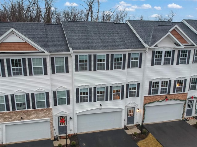 view of property with driveway, a shingled roof, and an attached garage