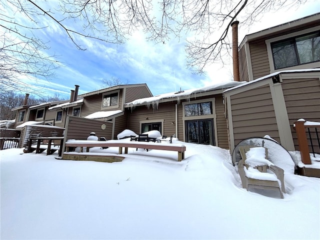 snow covered rear of property featuring a chimney