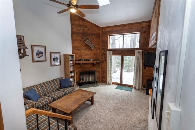 living room with carpet floors, a fireplace with flush hearth, and wooden walls