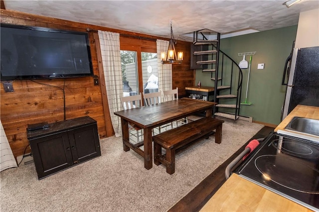 dining room with stairs, wood walls, a chandelier, and light colored carpet