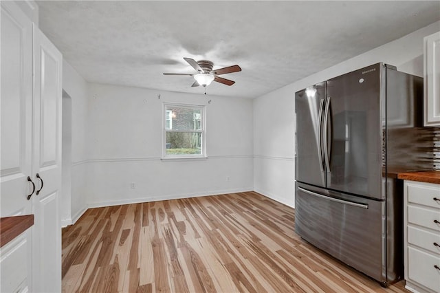 kitchen with ceiling fan, butcher block countertops, white cabinets, light wood-type flooring, and freestanding refrigerator