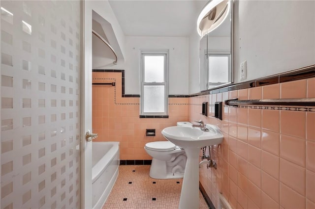 bathroom featuring tile patterned flooring, wainscoting, tile walls, and toilet