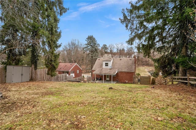 view of yard with a storage unit, an outdoor structure, and a fenced backyard