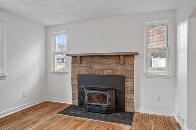 details with a wood stove, baseboards, and wood finished floors