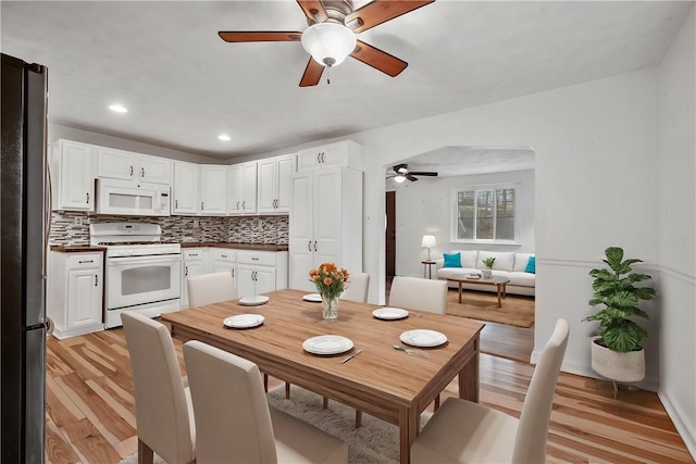 kitchen with light wood-type flooring, white appliances, white cabinetry, and decorative backsplash