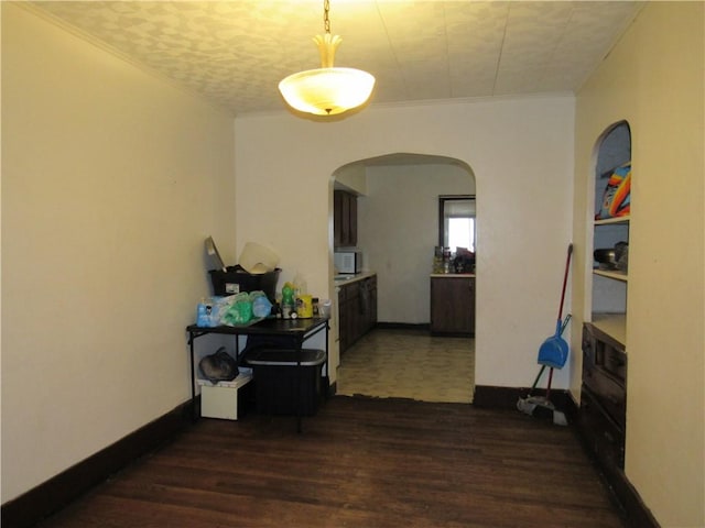 corridor with dark wood-type flooring, arched walkways, crown molding, and baseboards