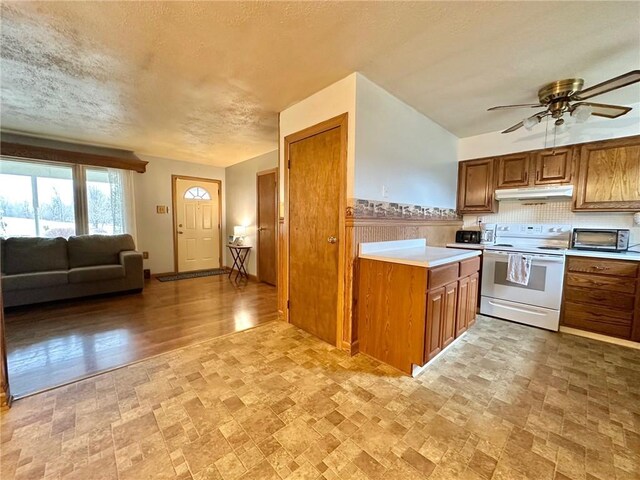 kitchen with brown cabinetry, white range with electric cooktop, under cabinet range hood, and light countertops