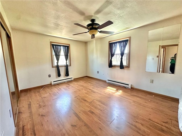 spare room featuring baseboard heating, a wealth of natural light, and a textured ceiling