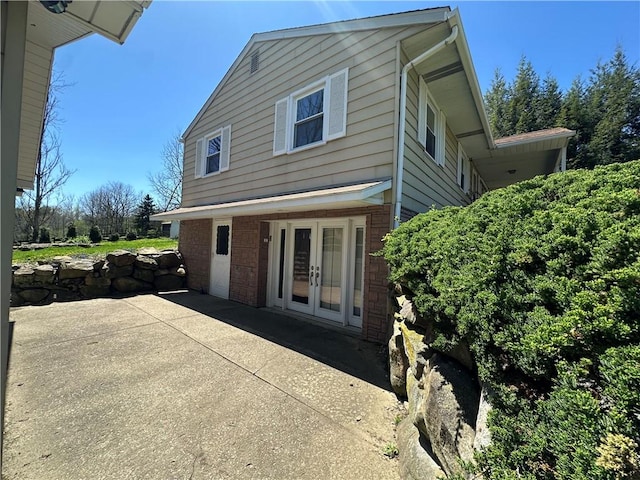 view of side of home with brick siding, french doors, and a patio area