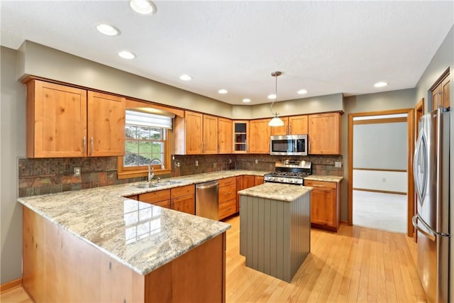 kitchen featuring decorative light fixtures, stainless steel appliances, a sink, a kitchen island, and glass insert cabinets