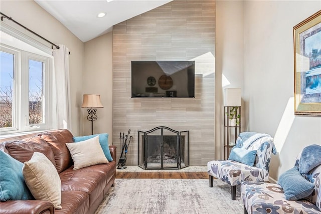 living area featuring vaulted ceiling, a fireplace, light wood-style flooring, and recessed lighting