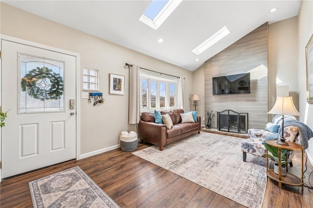 living room featuring a large fireplace, baseboards, lofted ceiling with skylight, dark wood-type flooring, and recessed lighting