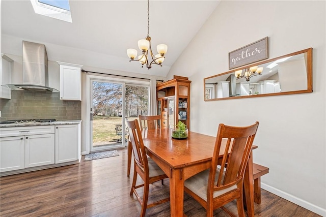 dining room featuring a chandelier, vaulted ceiling with skylight, dark wood finished floors, and baseboards