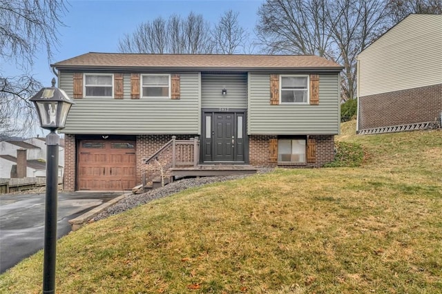 raised ranch with aphalt driveway, a front yard, and brick siding