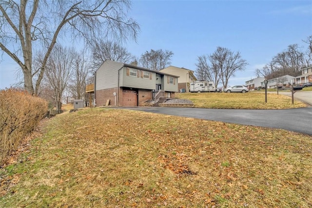 view of front of house featuring driveway, a garage, a residential view, a front yard, and brick siding