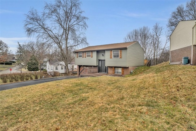 bi-level home with aphalt driveway, a front yard, and brick siding