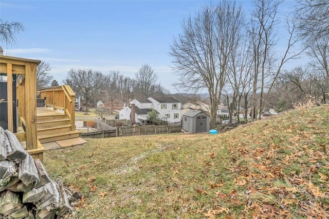 view of yard with a residential view, an outbuilding, fence, a deck, and a shed