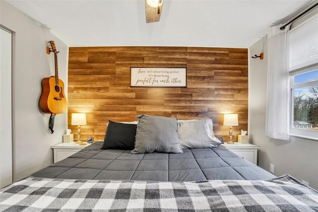 unfurnished bedroom featuring ceiling fan, an accent wall, and wood walls