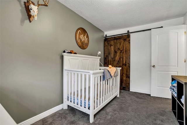 bedroom featuring a textured ceiling, dark colored carpet, a barn door, and baseboards