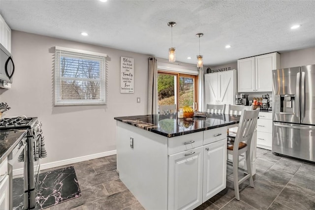 kitchen featuring pendant lighting, appliances with stainless steel finishes, a kitchen island, and white cabinets