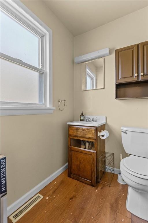 bathroom featuring toilet, baseboards, visible vents, and wood finished floors