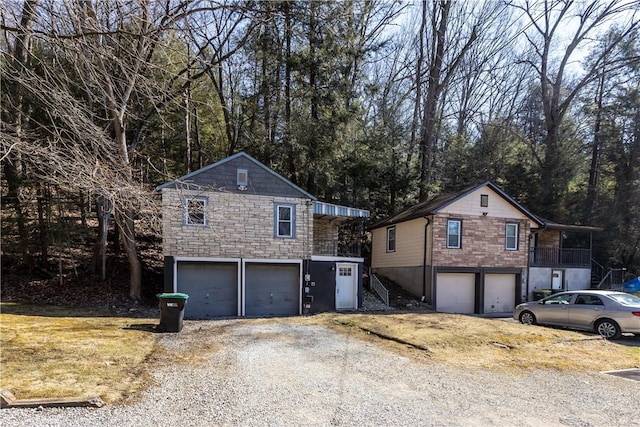 view of front facade with an attached garage, stone siding, and driveway