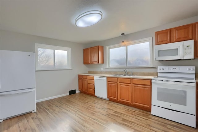 kitchen with white appliances, baseboards, light wood-style floors, and a sink