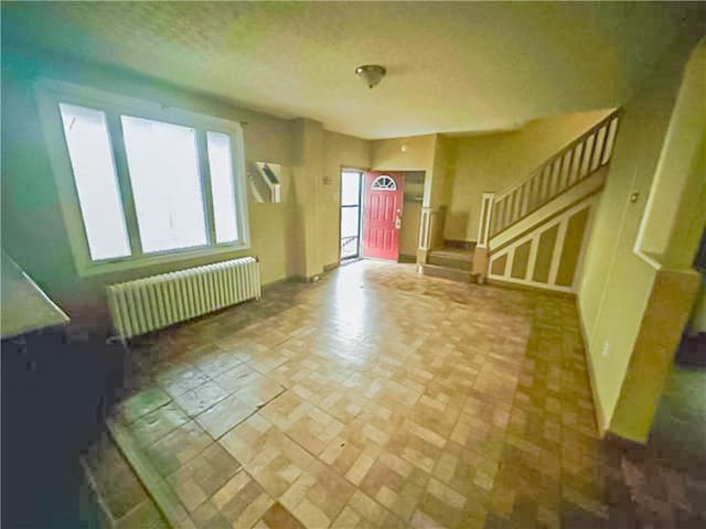 unfurnished living room with stairs and radiator