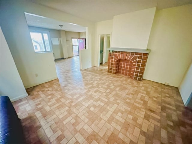 unfurnished living room featuring brick floor, baseboards, and a tiled fireplace