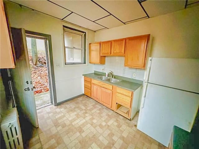 kitchen with backsplash, a sink, and freestanding refrigerator