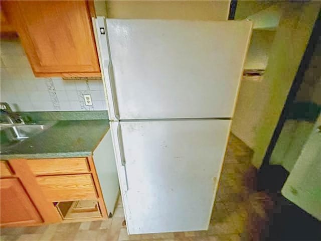 kitchen featuring tasteful backsplash, a sink, and freestanding refrigerator