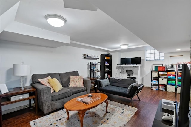 living area featuring a raised ceiling, wood finished floors, and baseboards