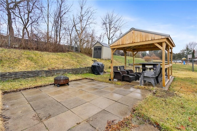 view of patio with a fire pit, a storage shed, an outdoor structure, fence, and a gazebo