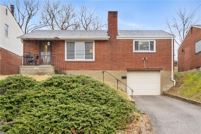 exterior space with brick siding, a chimney, a shingled roof, a garage, and driveway