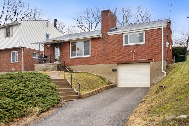 view of front of house featuring a garage, brick siding, a chimney, and aphalt driveway