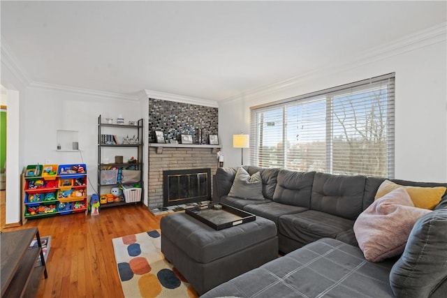 living room with ornamental molding, a brick fireplace, and wood finished floors