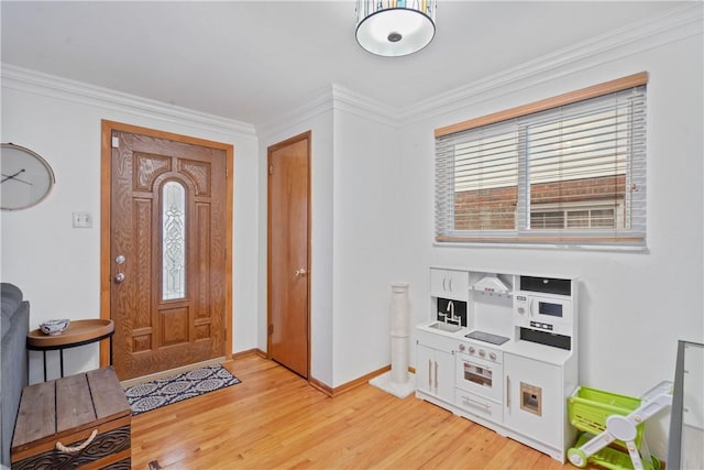 foyer entrance featuring baseboards, crown molding, and light wood finished floors