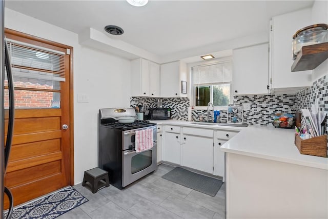 kitchen featuring decorative backsplash, light countertops, double oven range, white cabinetry, and a sink