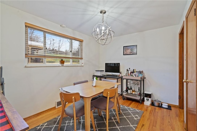 dining room with a notable chandelier, baseboards, and wood finished floors