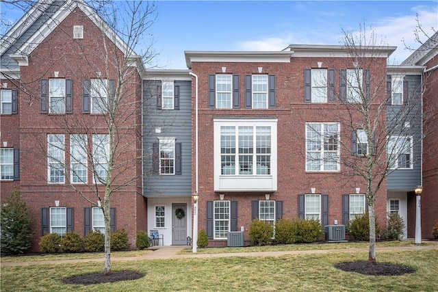 multi unit property featuring a front yard, cooling unit, and brick siding