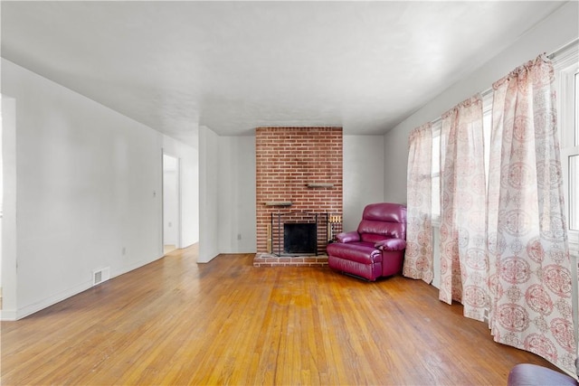 unfurnished living room with wood-type flooring, a fireplace, and visible vents