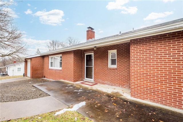 rear view of property featuring a patio area, brick siding, and a chimney