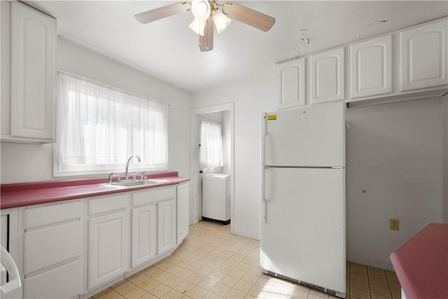 kitchen with freestanding refrigerator, white cabinetry, a sink, ceiling fan, and baseboards