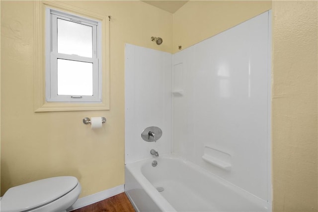 bathroom featuring toilet, bathtub / shower combination, baseboards, and wood finished floors