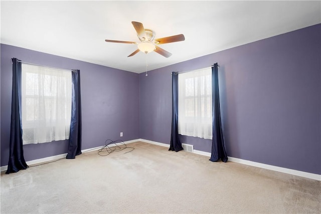 carpeted empty room with visible vents, a ceiling fan, and baseboards