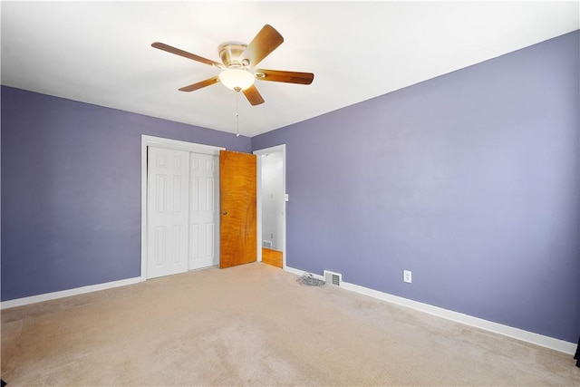 unfurnished bedroom with carpet, a closet, visible vents, a ceiling fan, and baseboards