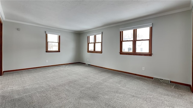 carpeted spare room with baseboards, a textured ceiling, visible vents, and crown molding